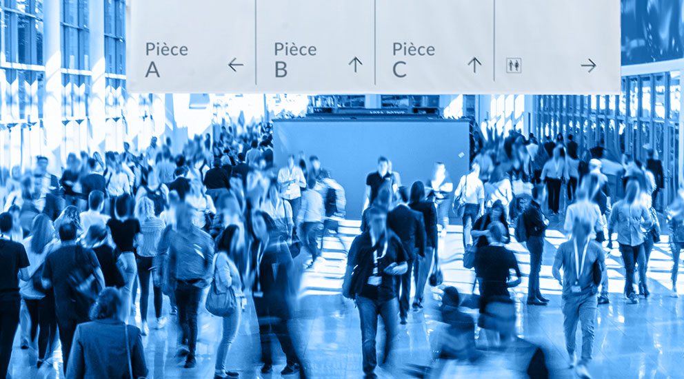 A trade show exhibition hall with lots of people and signage showing direction of different exhibits
