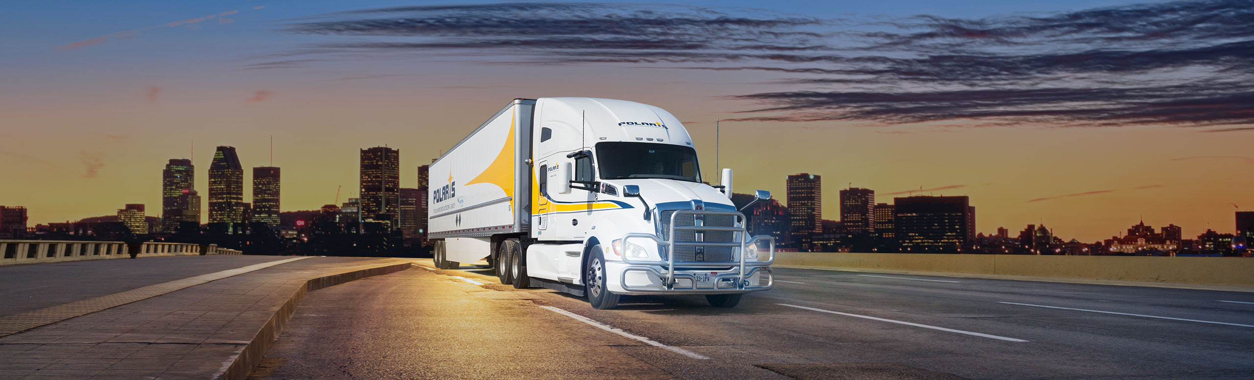 Polaris semi-trailer driving on freeway with cityscape in background 