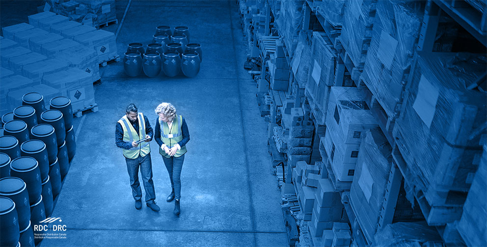 Interior of warehouse with two staff walking and reviewing warehouse management system